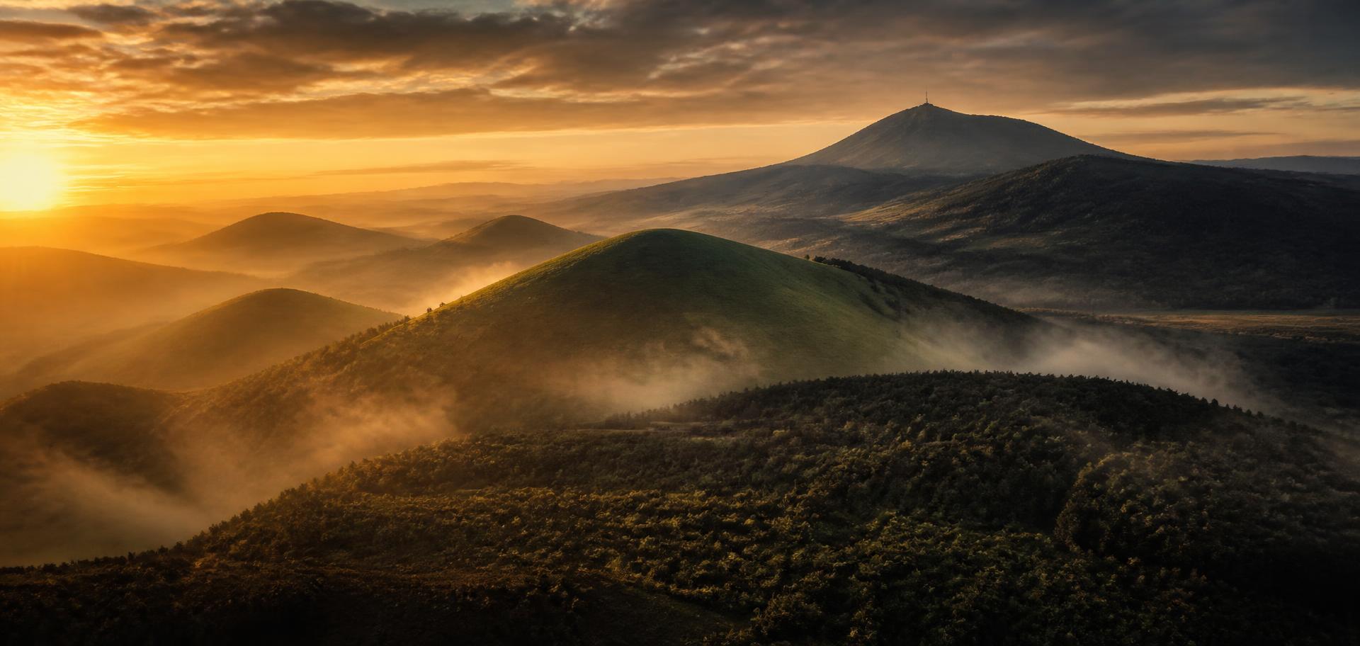 Volcanic hills of the Auvergne region at sunrise with mist in the valleys