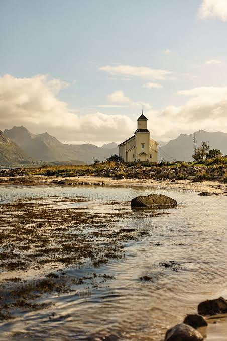 White wooden church on the Lofoten shoreline at golden hour