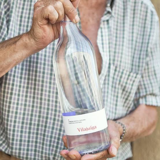 A litre glass bottle of Vilajuïga held in a farmer's hands