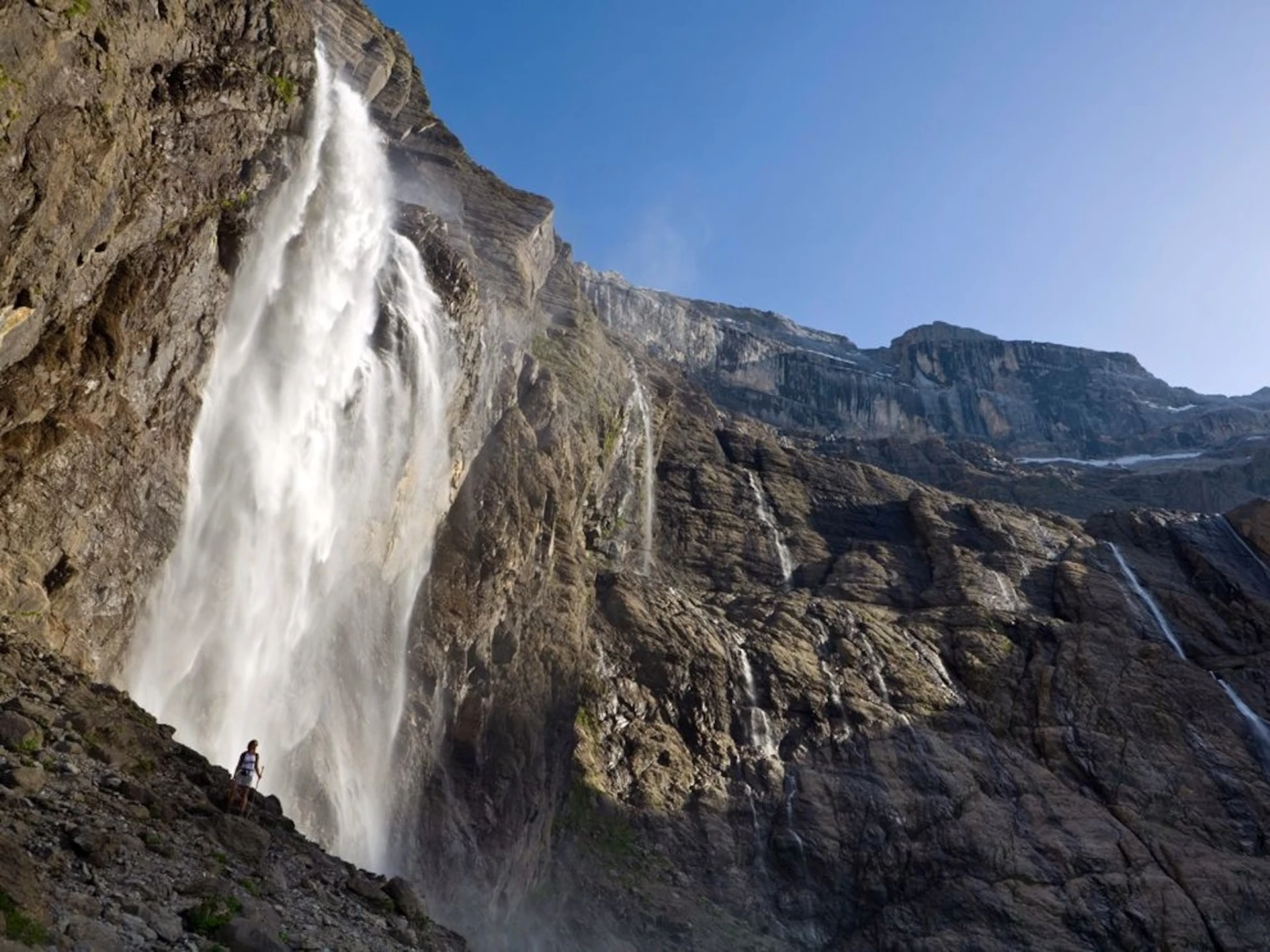 A tall waterfall falling from a limestone cirque wall in the Pyrenees