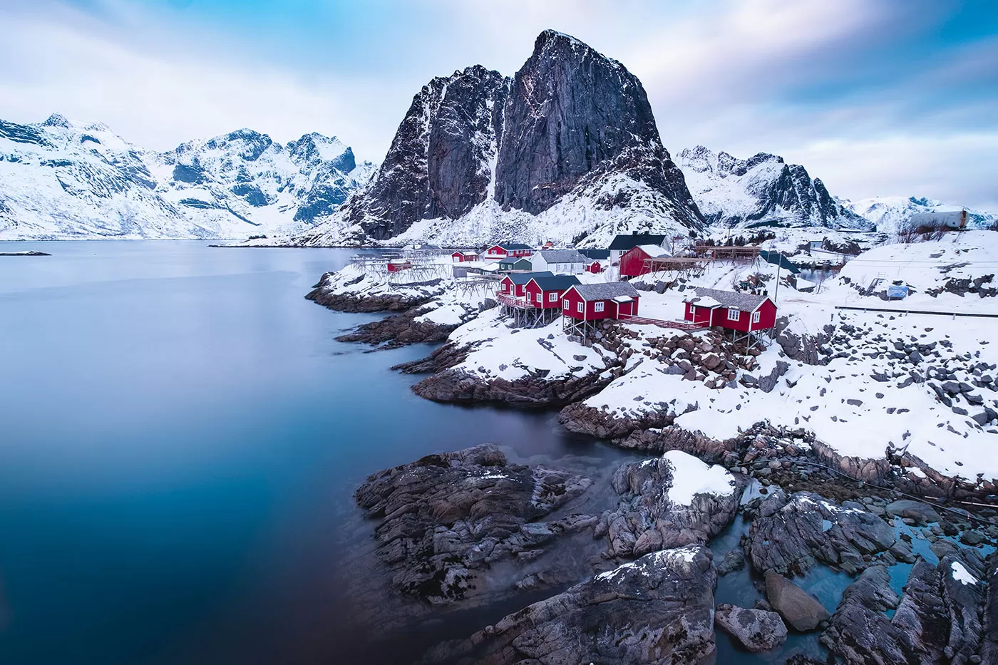 Red rorbuer cabins beneath a dark peak at Hamnøy in winter