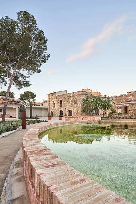 Restored stone masia beside a still spring-fed pool at dusk
