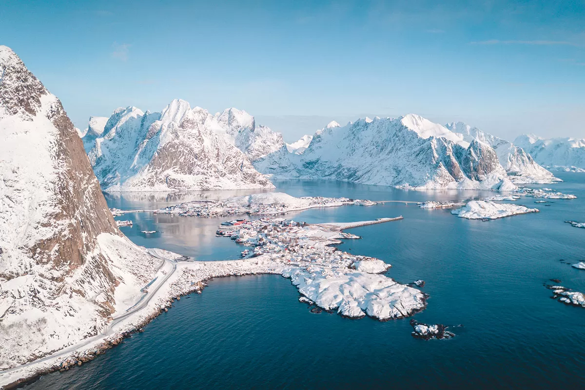 Snow-covered village and peaks above a fjord in Reine, Lofoten