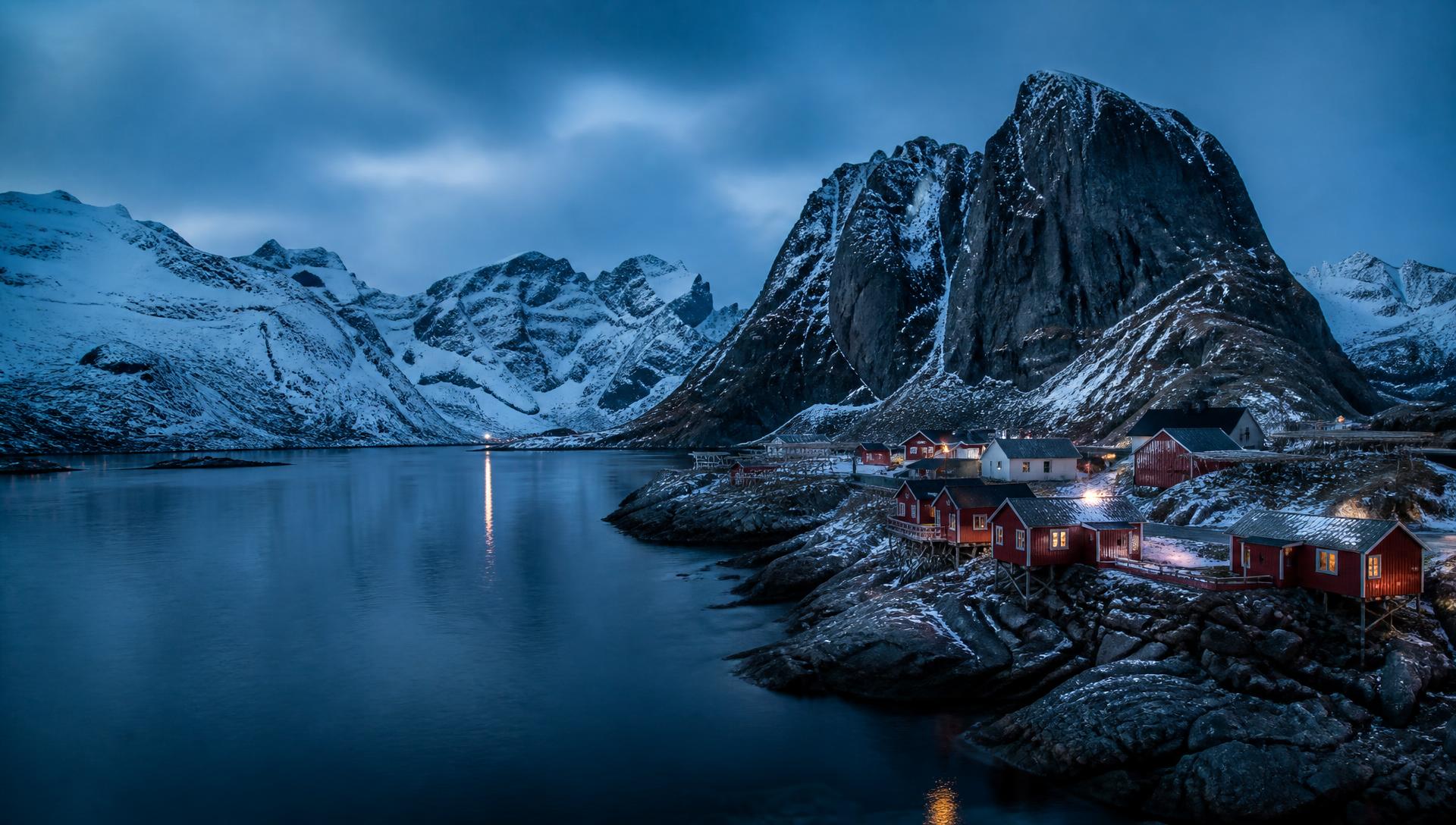 Snow-capped peaks and red cabins above a fjord in the Lofoten Islands, Norway